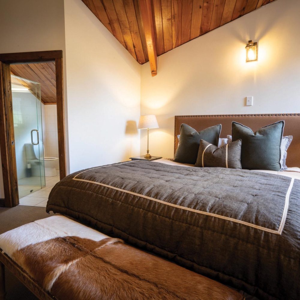 Bedroom in Kuranui Lodge with doorway leading to modern en-suite bathroom.